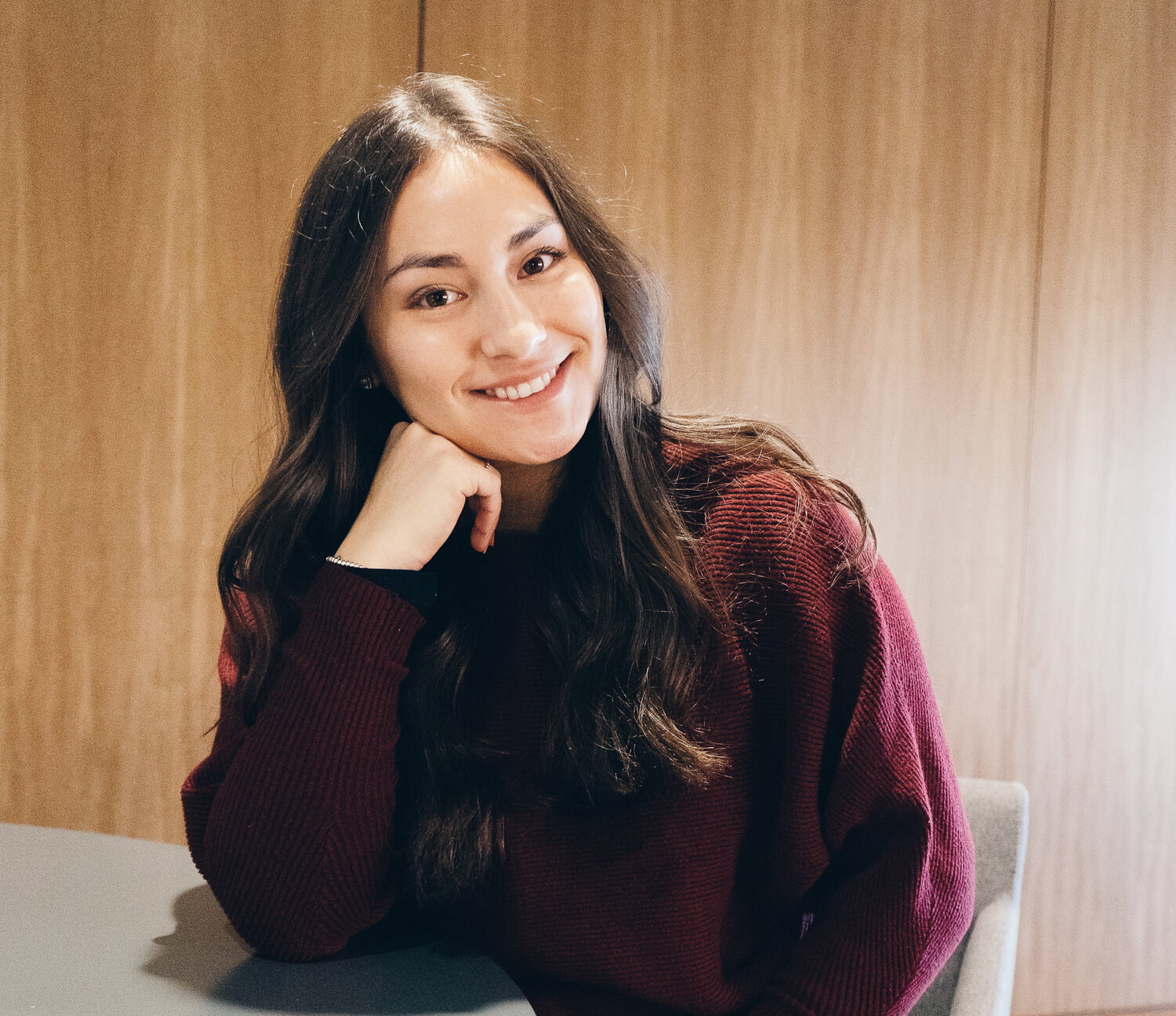 The founder, Nicole, posing for a photo with her elbow on a desk and smiling