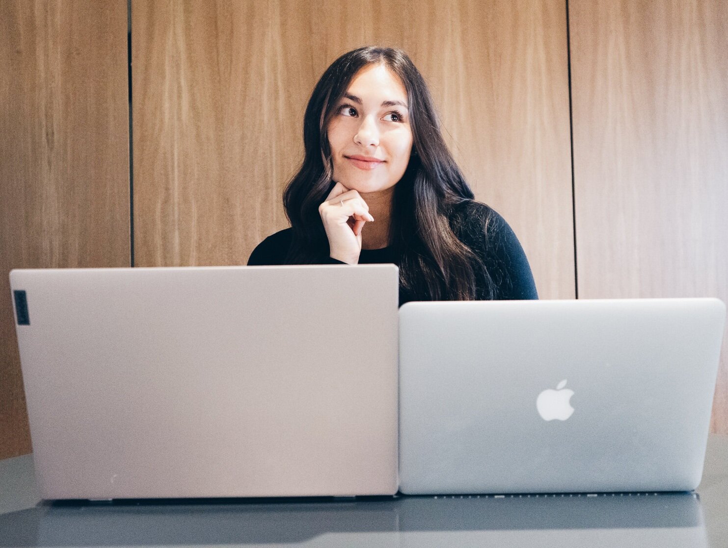 The founder, Nicole, posing for a photo with a windows computer and a mac computer